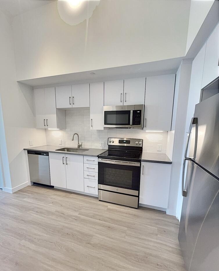 a kitchen with granite countertop a refrigerator stove and white cabinets