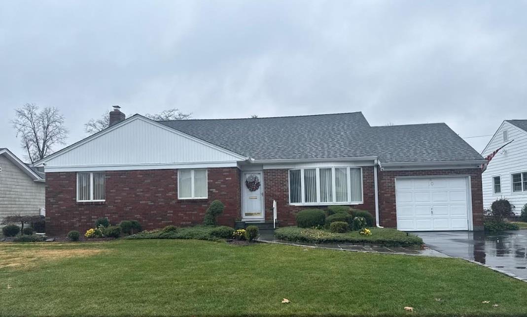 Single story home featuring a garage and a front lawn