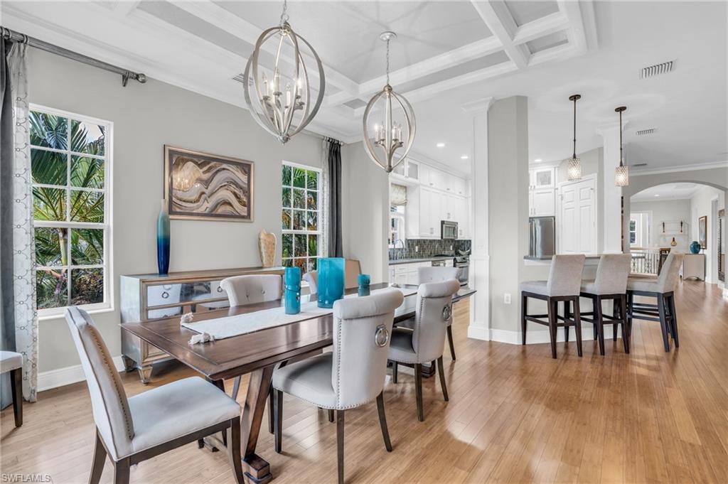 a dining room with wooden floor a chandelier a wooden table and chairs