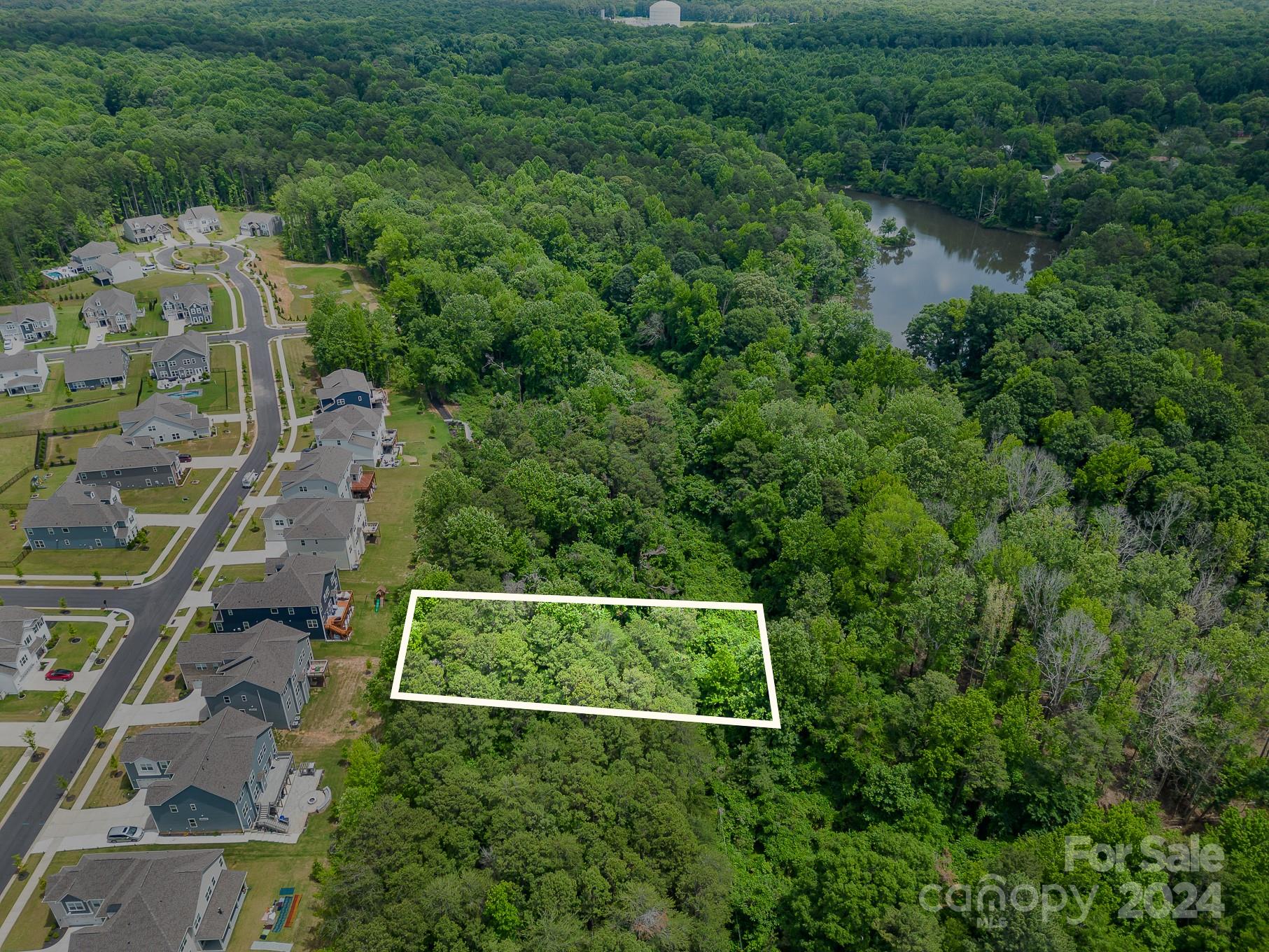 an aerial view of residential house with outdoor space and trees all around