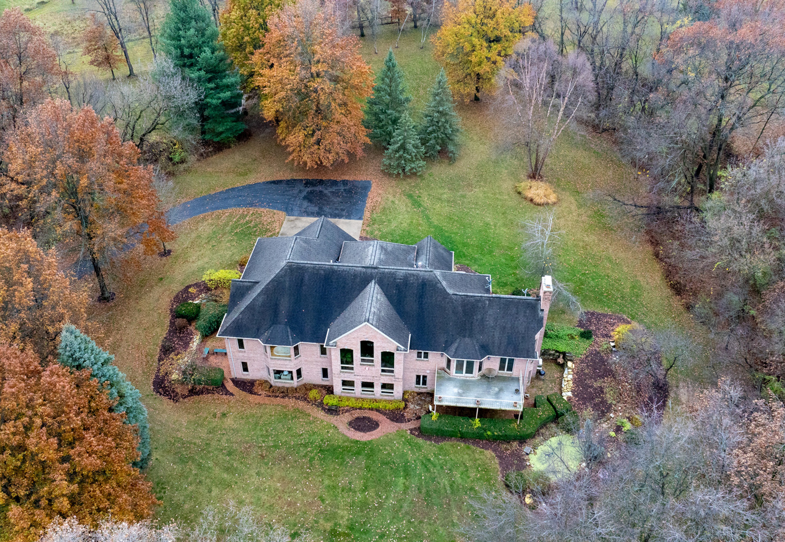 an aerial view of a house with swimming pool big yard and large trees