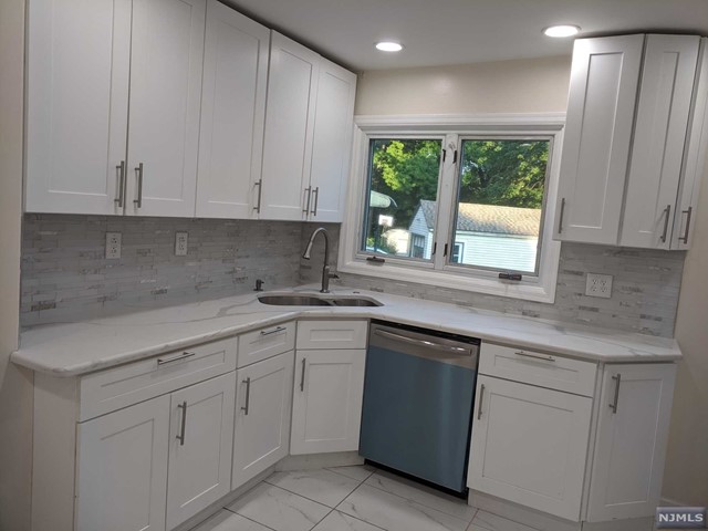 a kitchen with white cabinets and sink