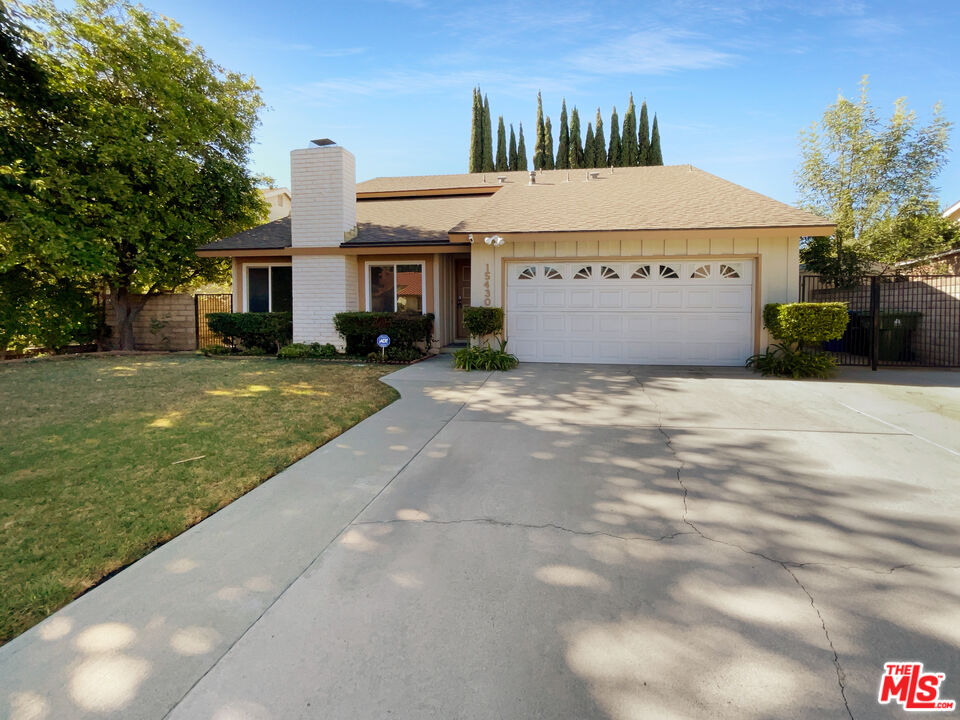 a view of a house with a yard and a large tree