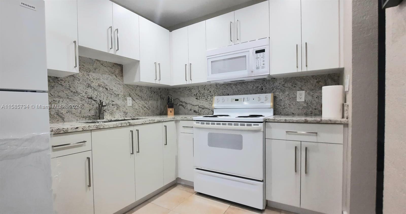 a kitchen with white cabinets and white appliances