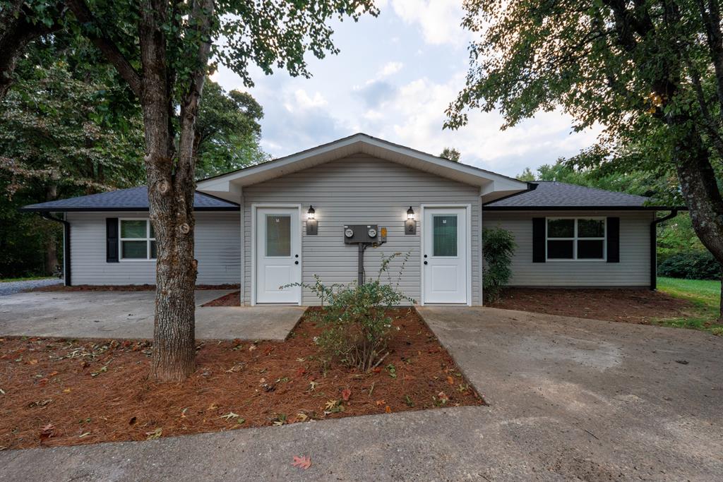 a view of a house with a yard and large tree