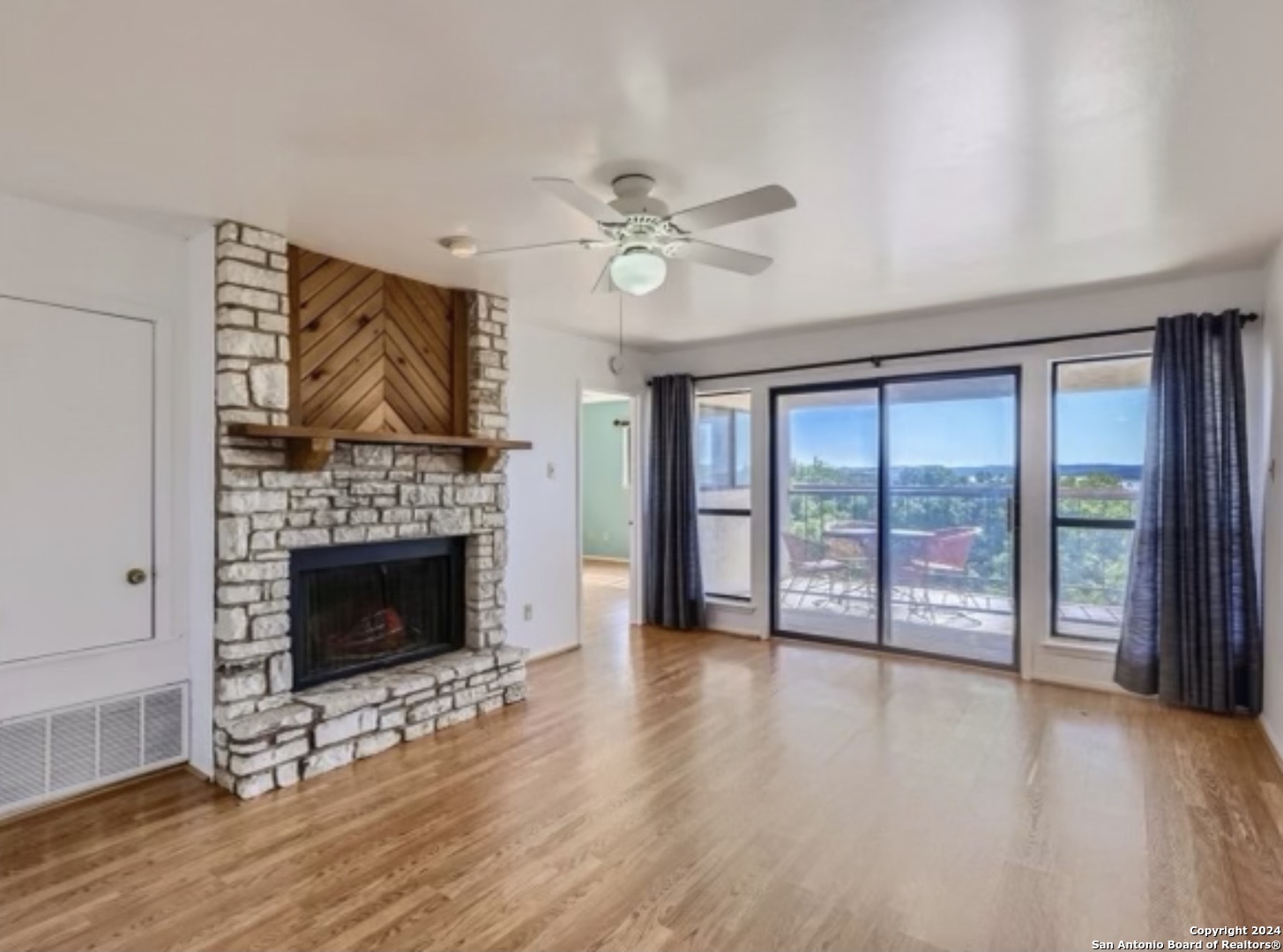 a view of an empty room with wooden floor and a fireplace