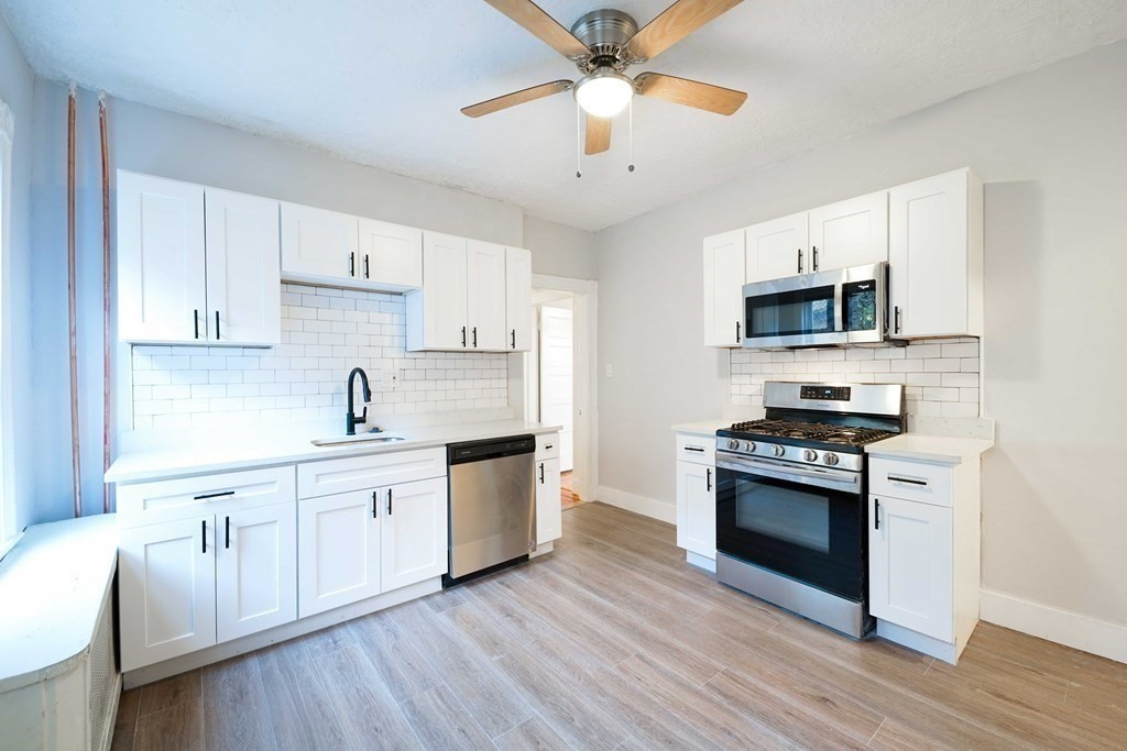 a kitchen with stainless steel appliances a white stove top oven cabinets and a wooden floor