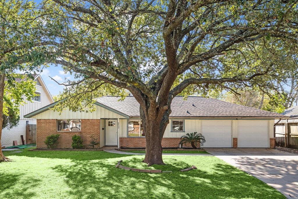 a view of a yard in front of a house with large tree