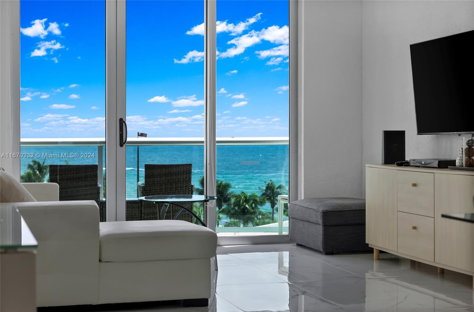 a living room with furniture a flat screen tv and a floor to ceiling window