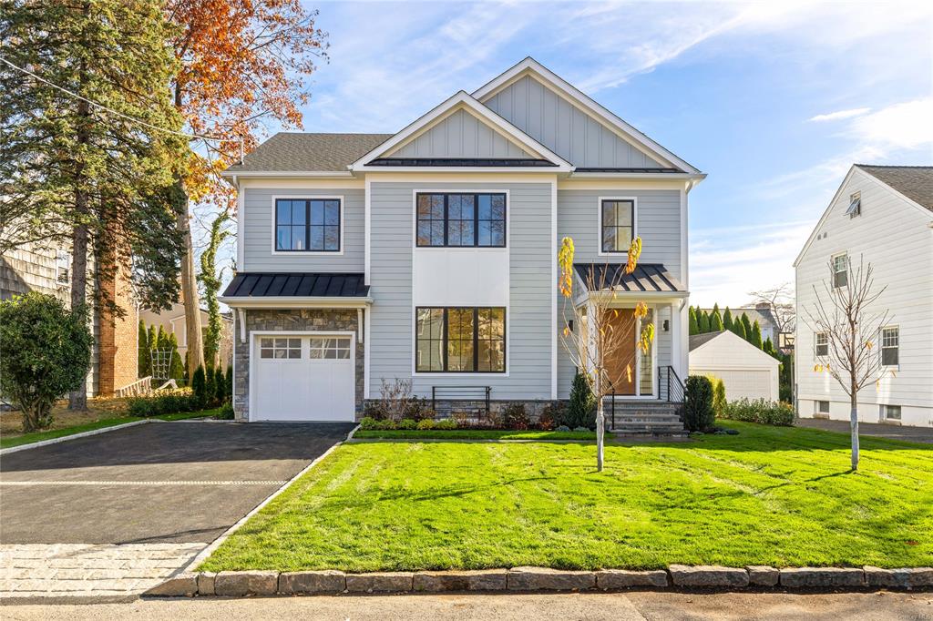 View of front facade featuring a front yard and a garage