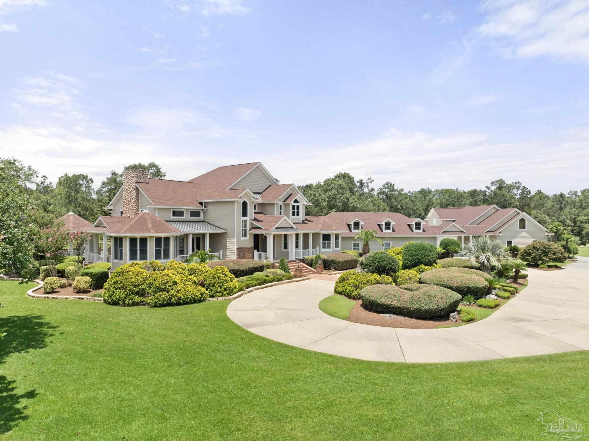 a view of a white house with a big yard and potted plants