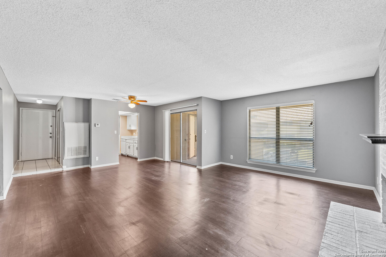 a view of an empty room with window and wooden floor