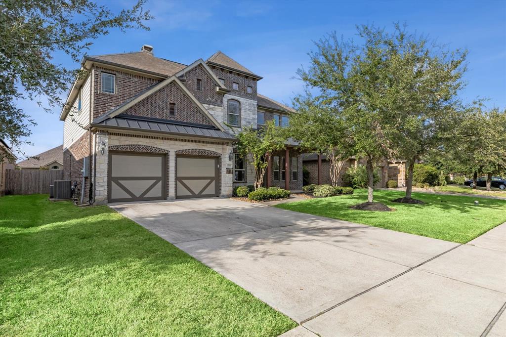 This is a spacious two-story brick home featuring a double garage, a well-manicured lawn with mature trees, and an inviting entryway.