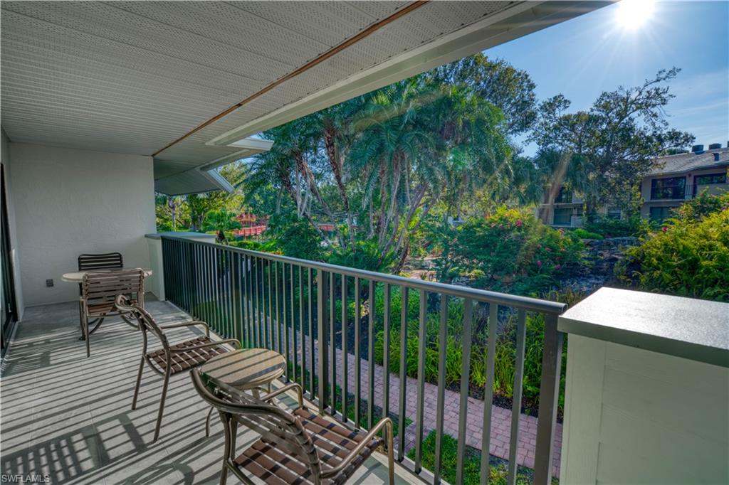 a balcony with wooden floor outdoor seating and yard in the back