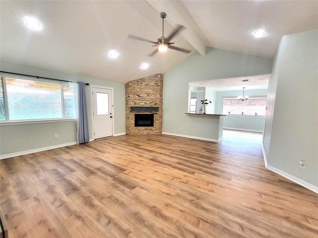 an empty room with wooden floor a ceiling fan and windows