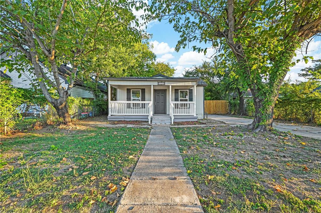 a view of a house with a small yard and large tree