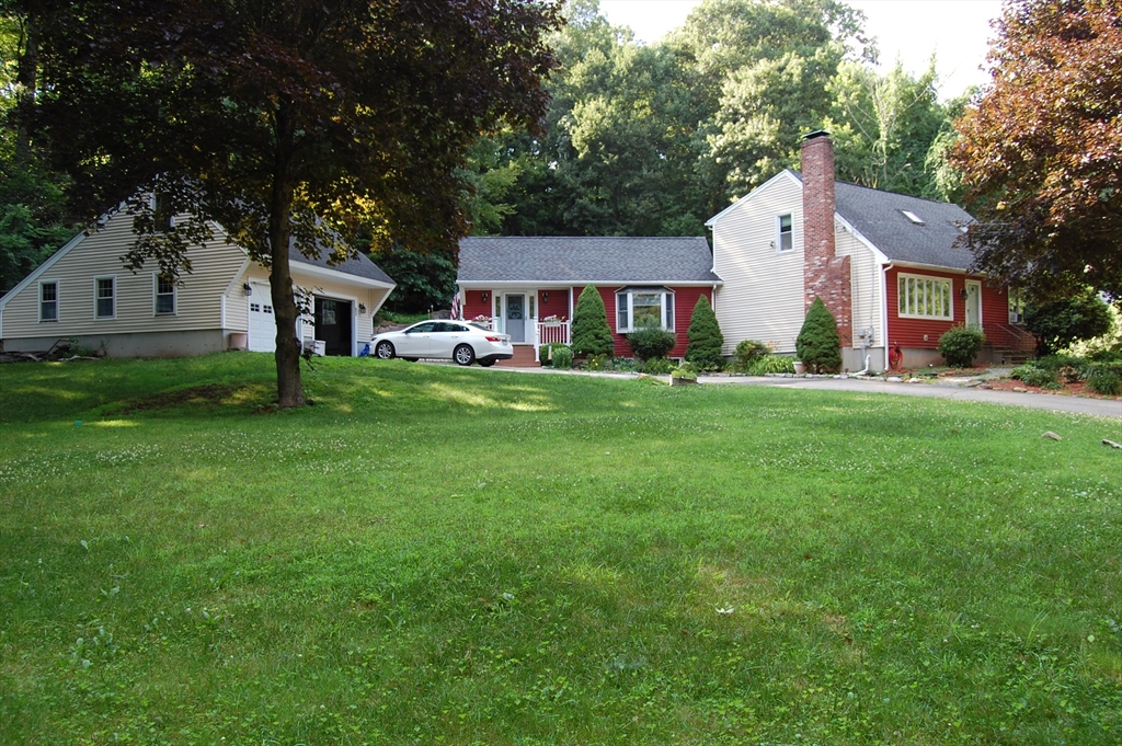 a front view of a house with a garden and trees