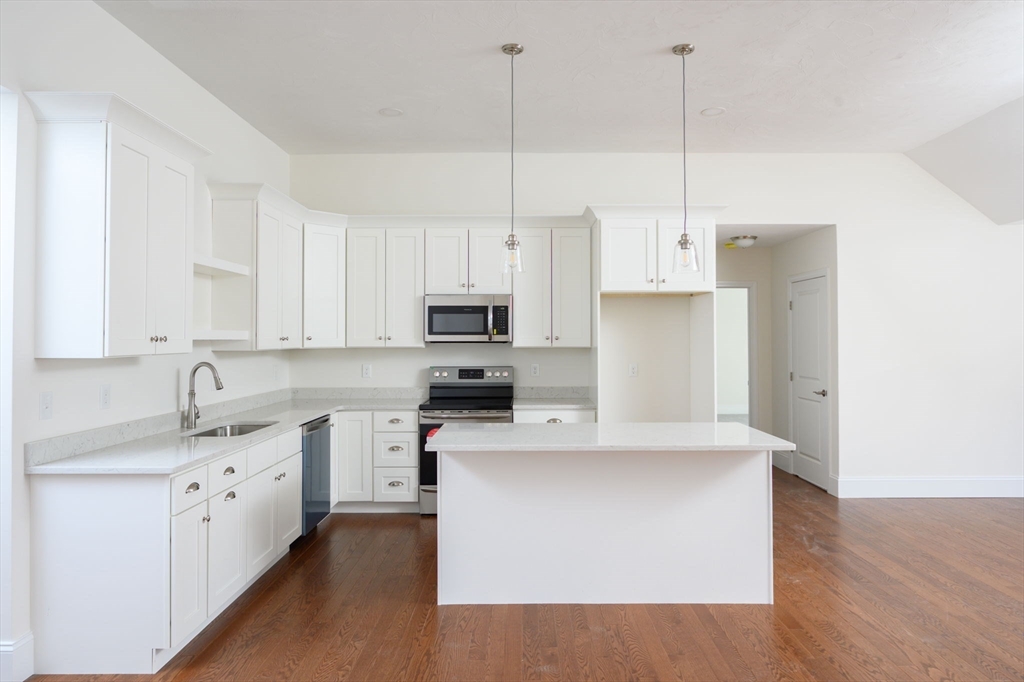 a kitchen with stainless steel appliances kitchen island a sink a stove and a wooden floor