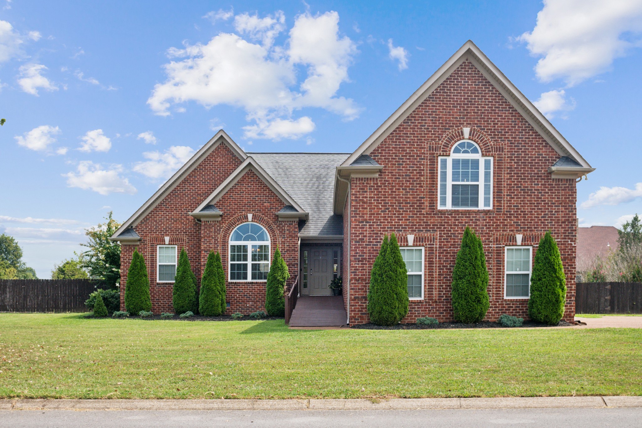 a front view of a house with yard and green space