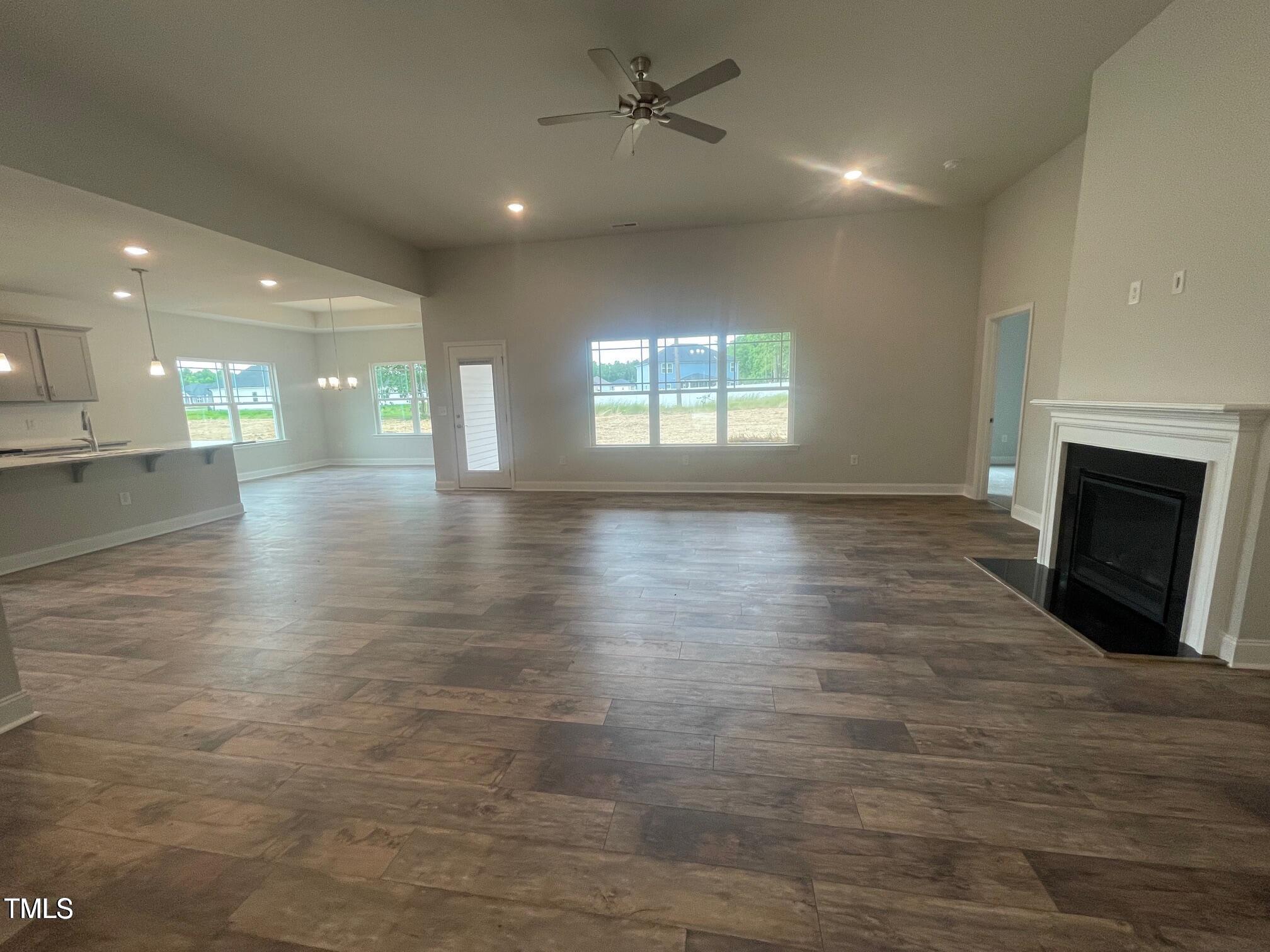 an empty room with wooden floor fireplace and windows