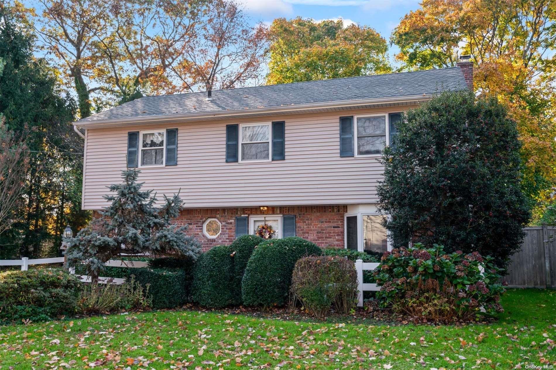 a view of a house with a yard plants and large tree