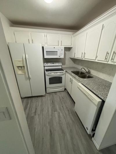 a kitchen with granite countertop white cabinets and white appliances