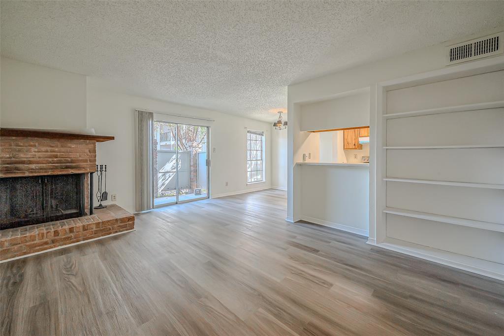 an empty room with wooden floor fireplace and windows