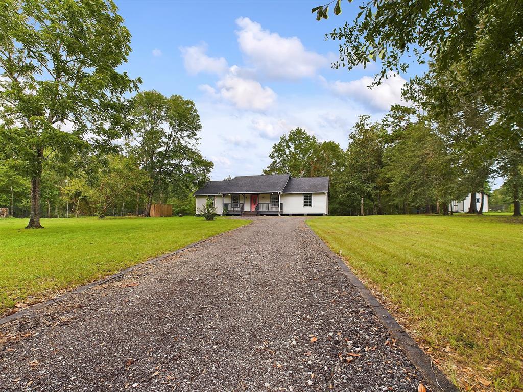 a white house with a big yard and large trees