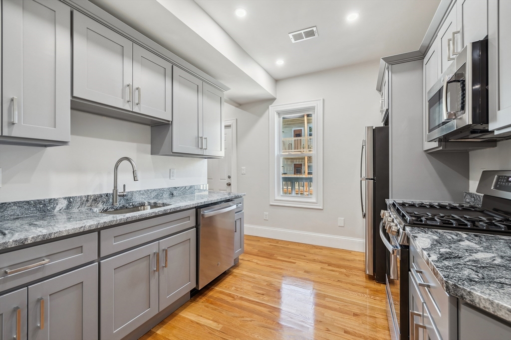 a kitchen with stainless steel appliances granite countertop a sink stove and cabinets