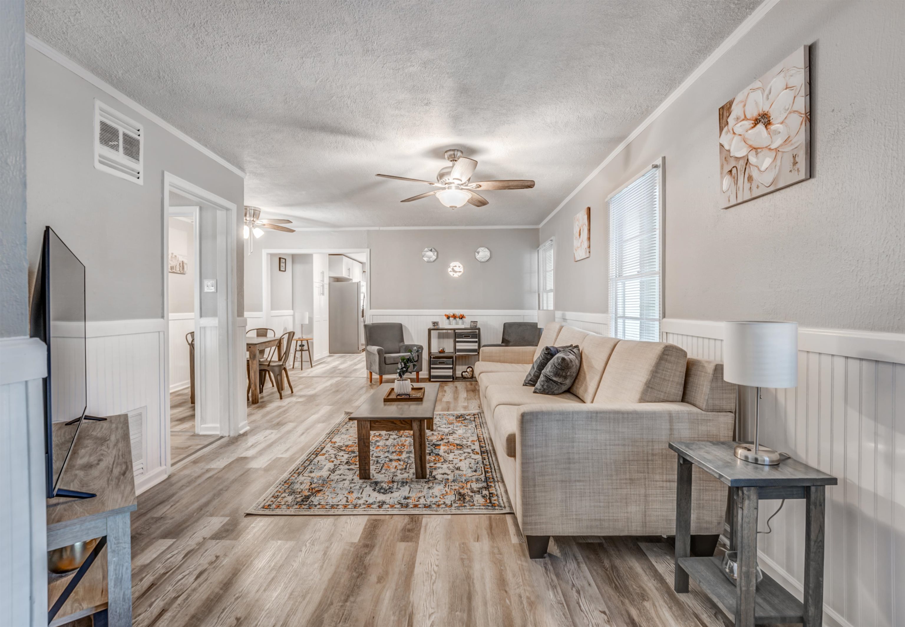 Living room with ceiling fan, a textured ceiling, light hardwood / wood-style flooring, and crown molding