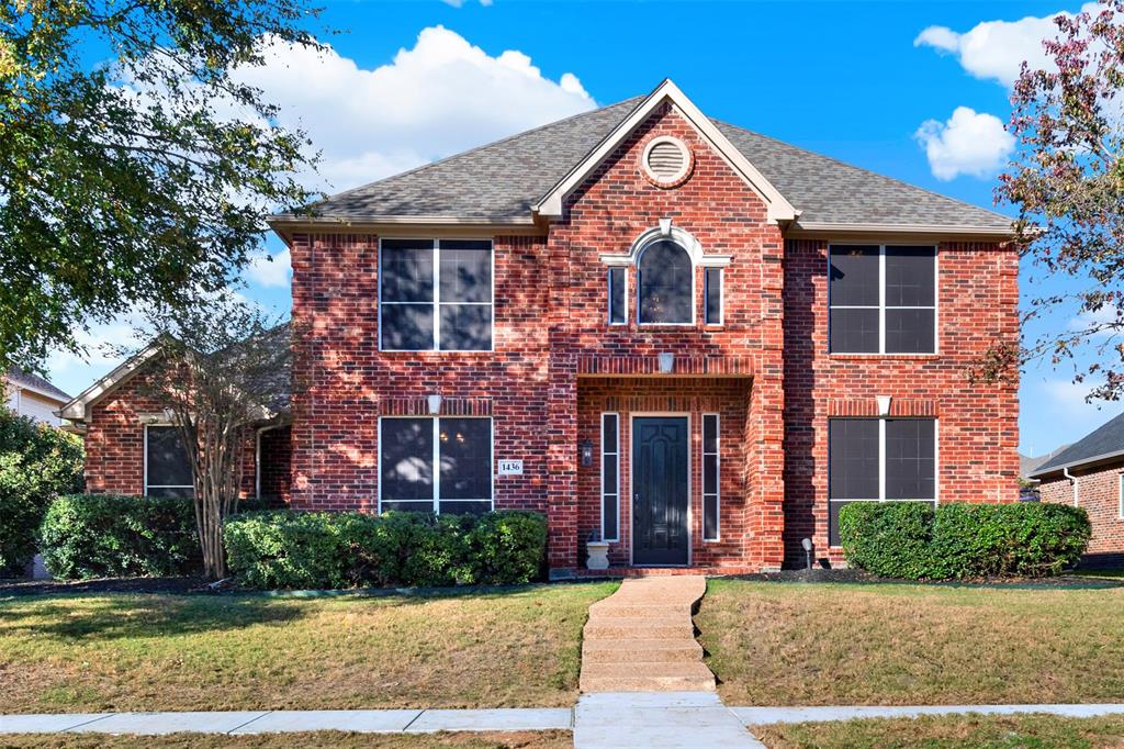 front view of a brick house with a yard