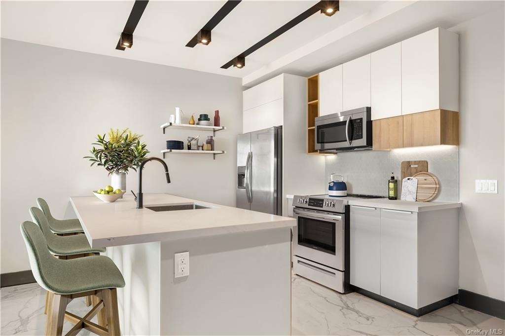 a kitchen with stainless steel appliances kitchen island a table chairs in it and white cabinets