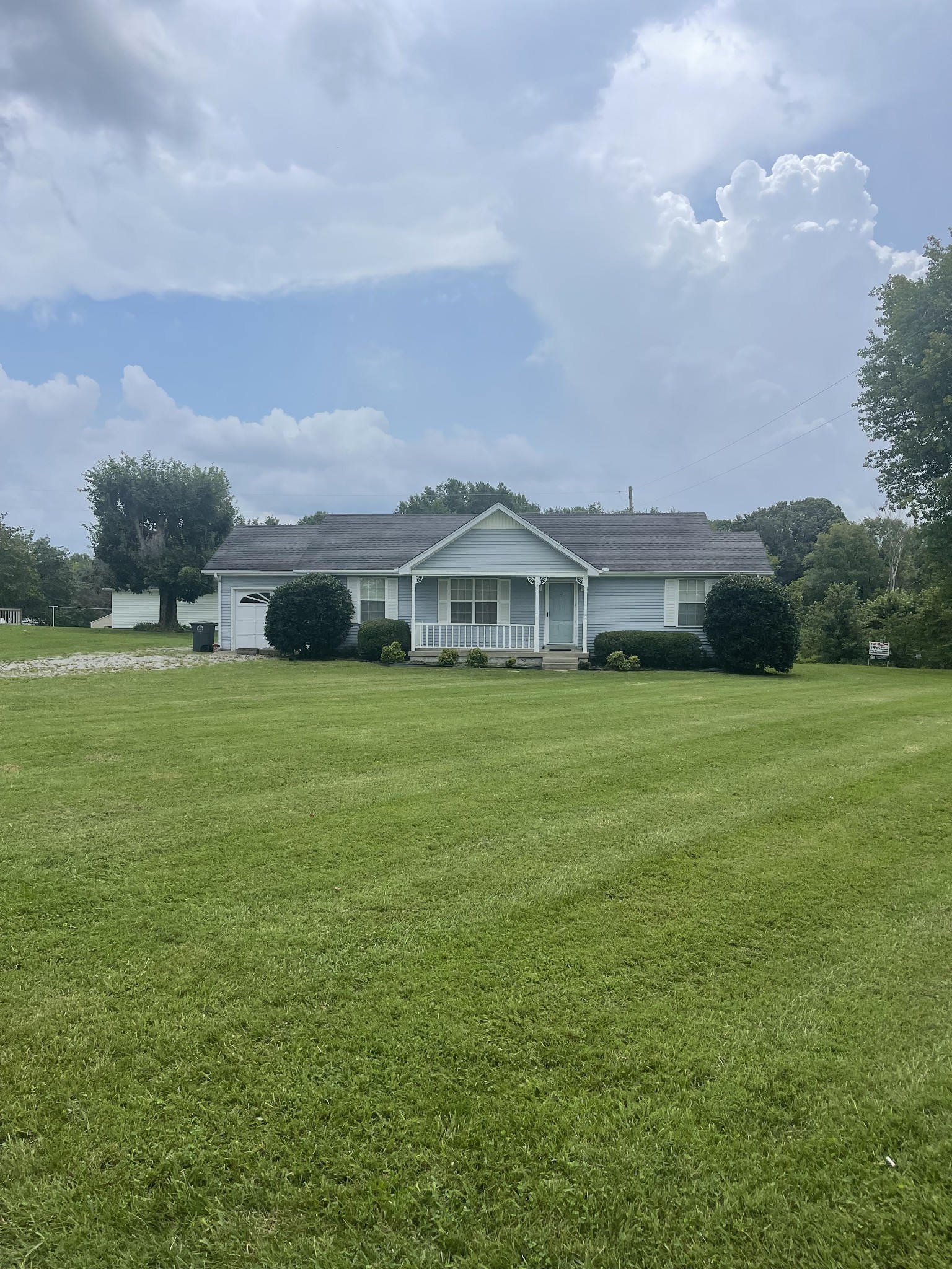 a view of a house with a big yard and large trees