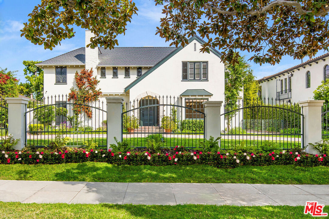 a front view of a house with a garden and trees