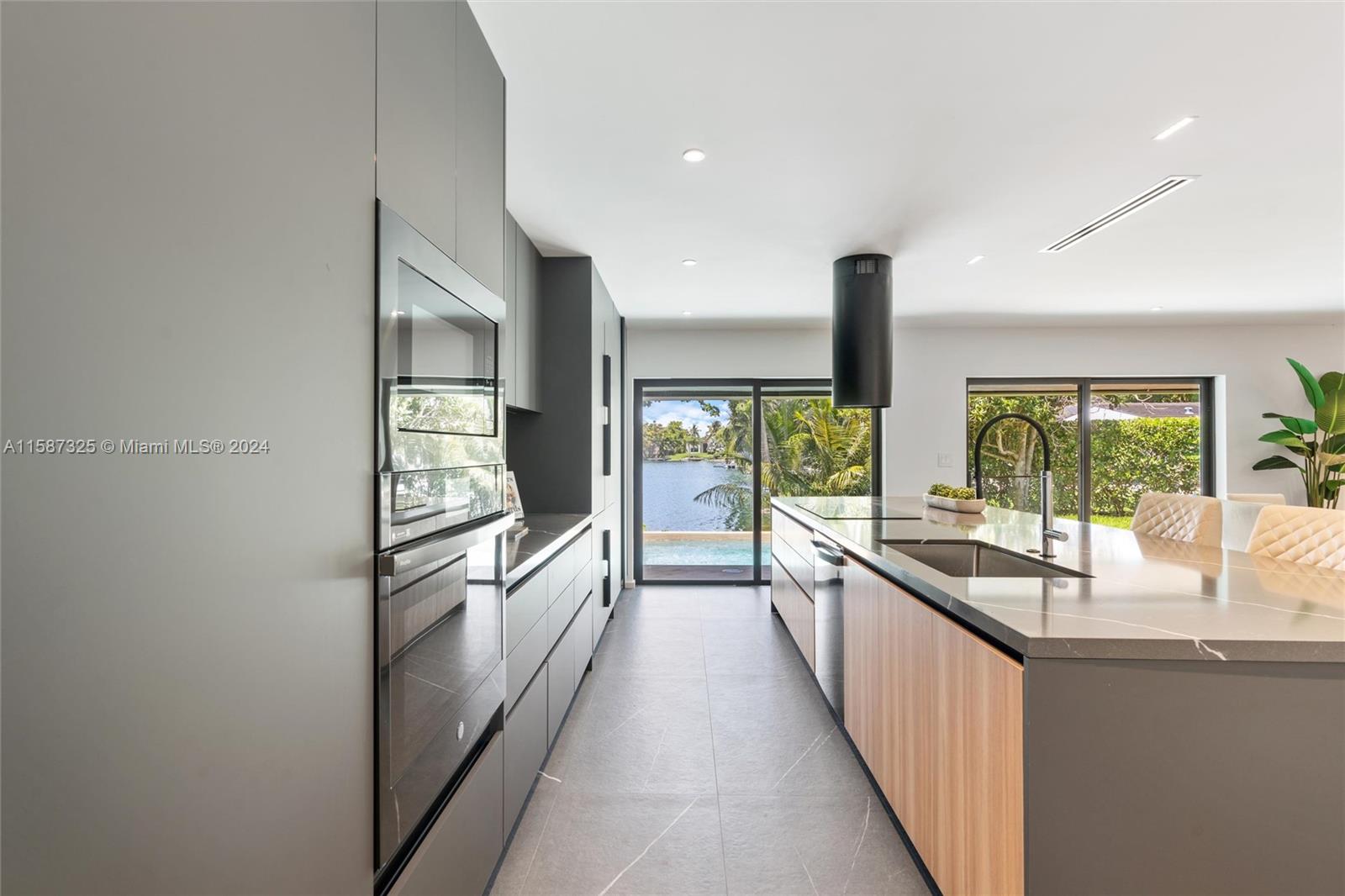 a large kitchen with kitchen island a large window a sink and stainless steel appliances