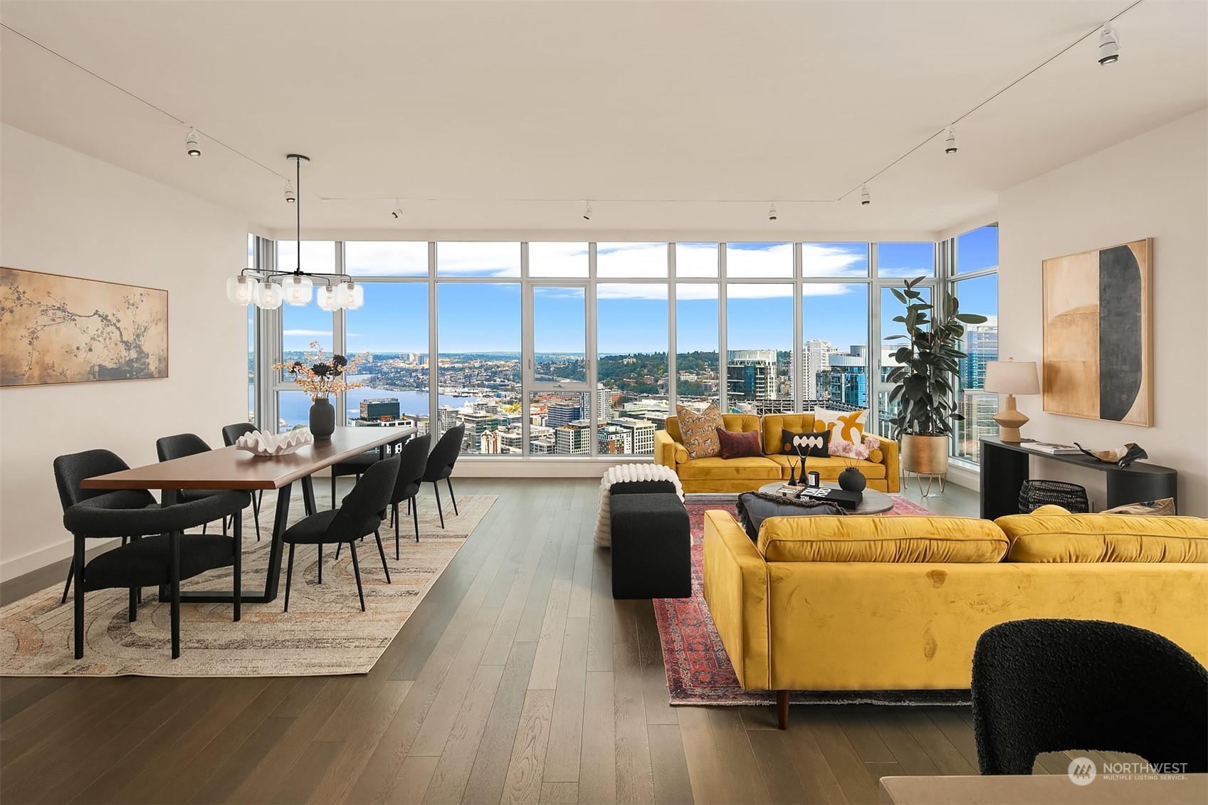 a living room with couches chairs and a dining table with wooden floor