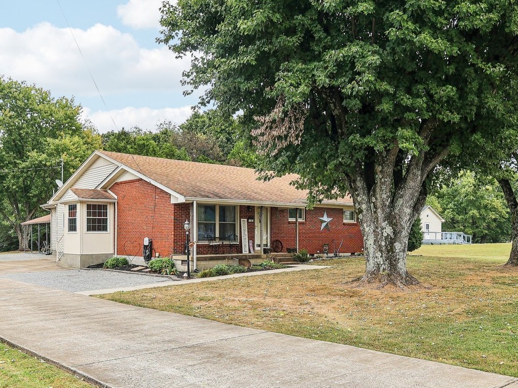 a front view of a house with a yard and large trees