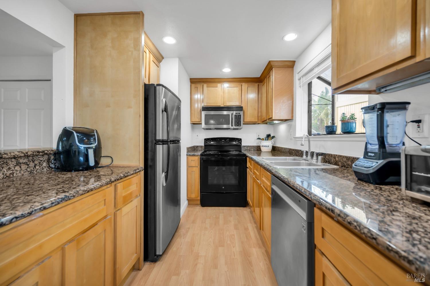 a kitchen with stainless steel appliances granite countertop a sink stove and refrigerator