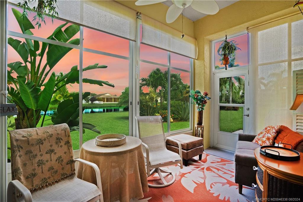 a view of a patio with table and chairs potted plants and a large window