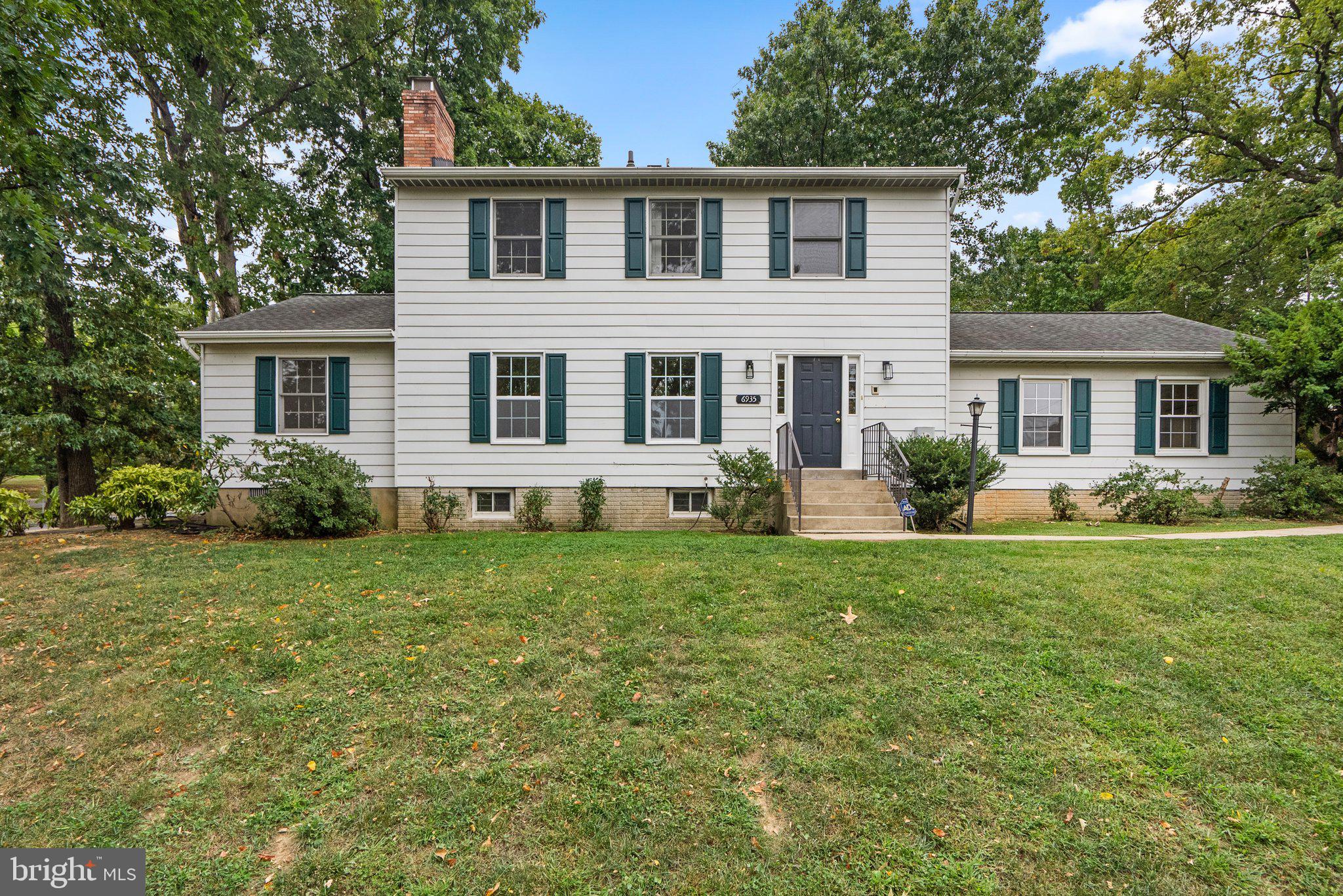 a front view of a house with a yard and green space