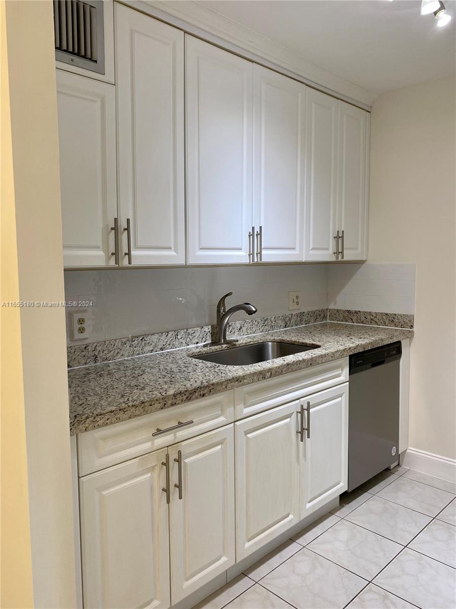 a kitchen with granite countertop white cabinets and sink