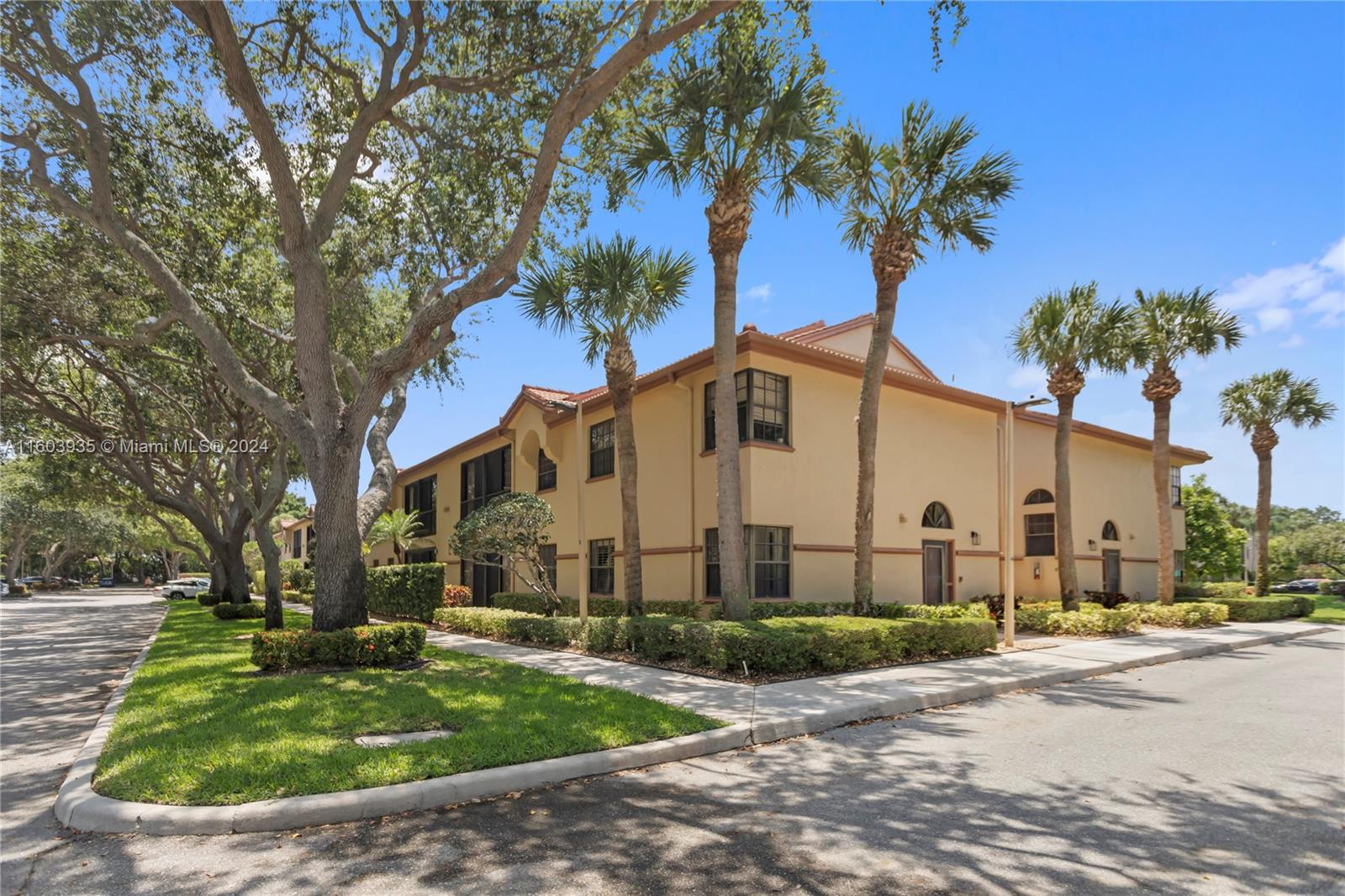 a view of a white house with a yard and palm trees