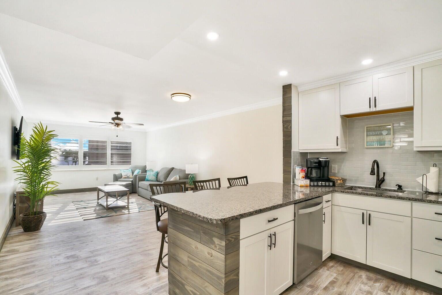 a kitchen with a sink dishwasher stove and white cabinets with wooden floor