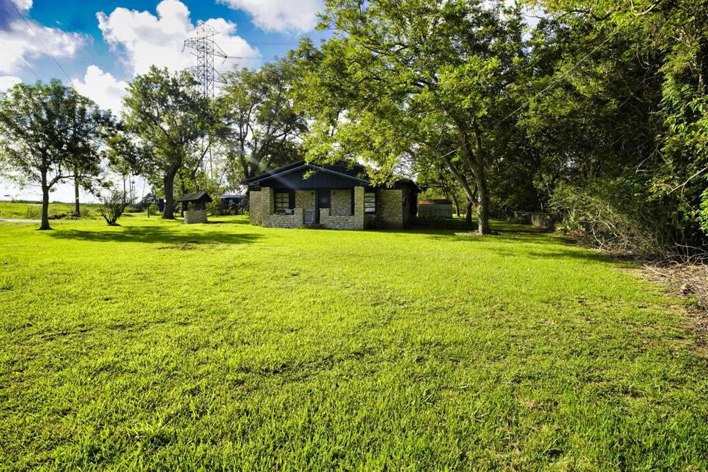 a brick house with a yard and large trees