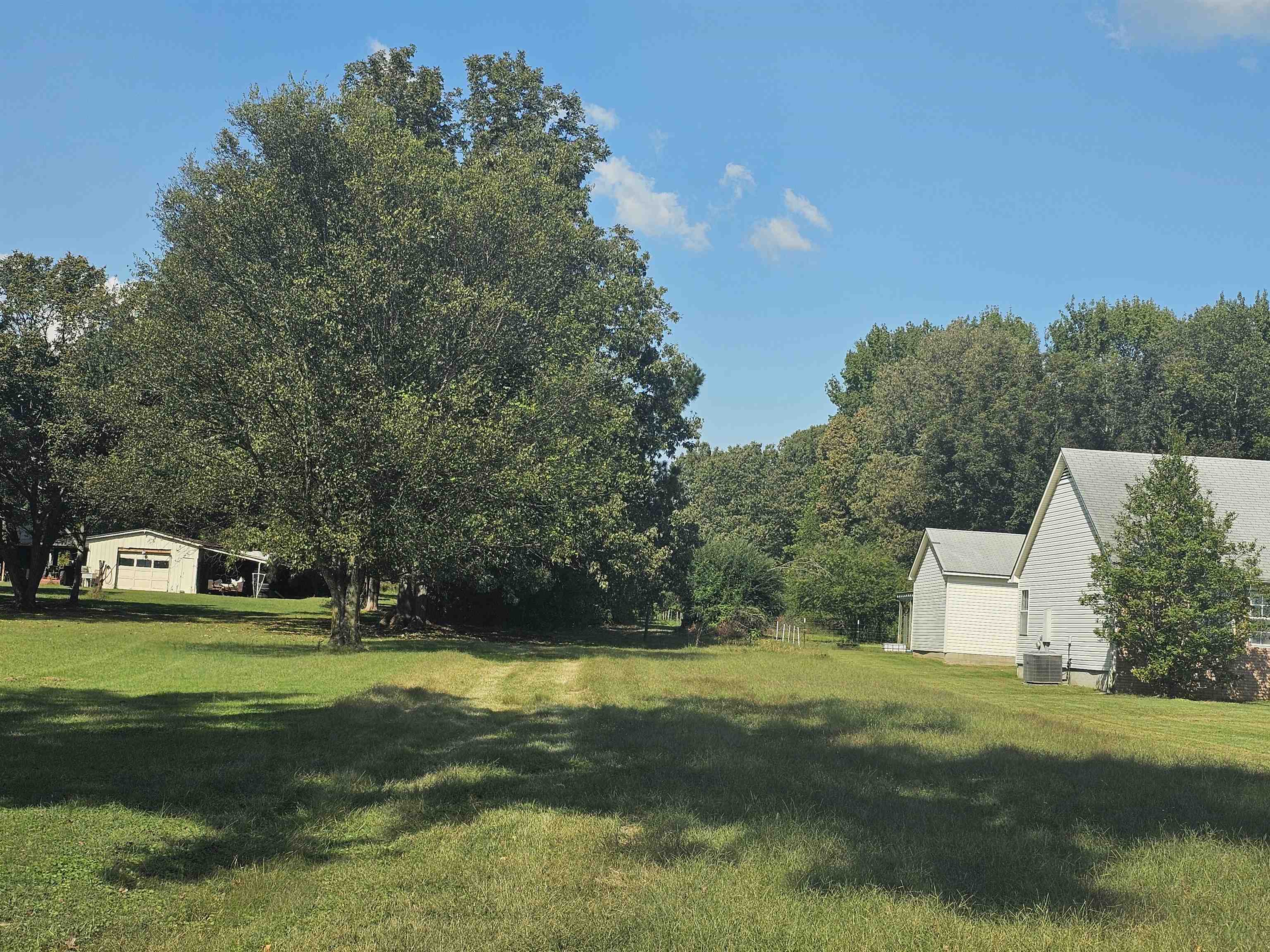 a view of a white house in a big yard with large trees