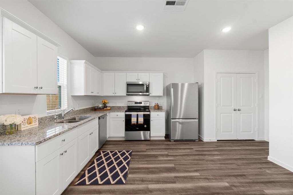 a kitchen with granite countertop white cabinets and stainless steel appliances