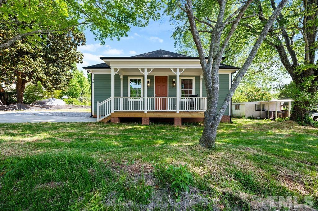 a view of a house with a backyard and a large tree