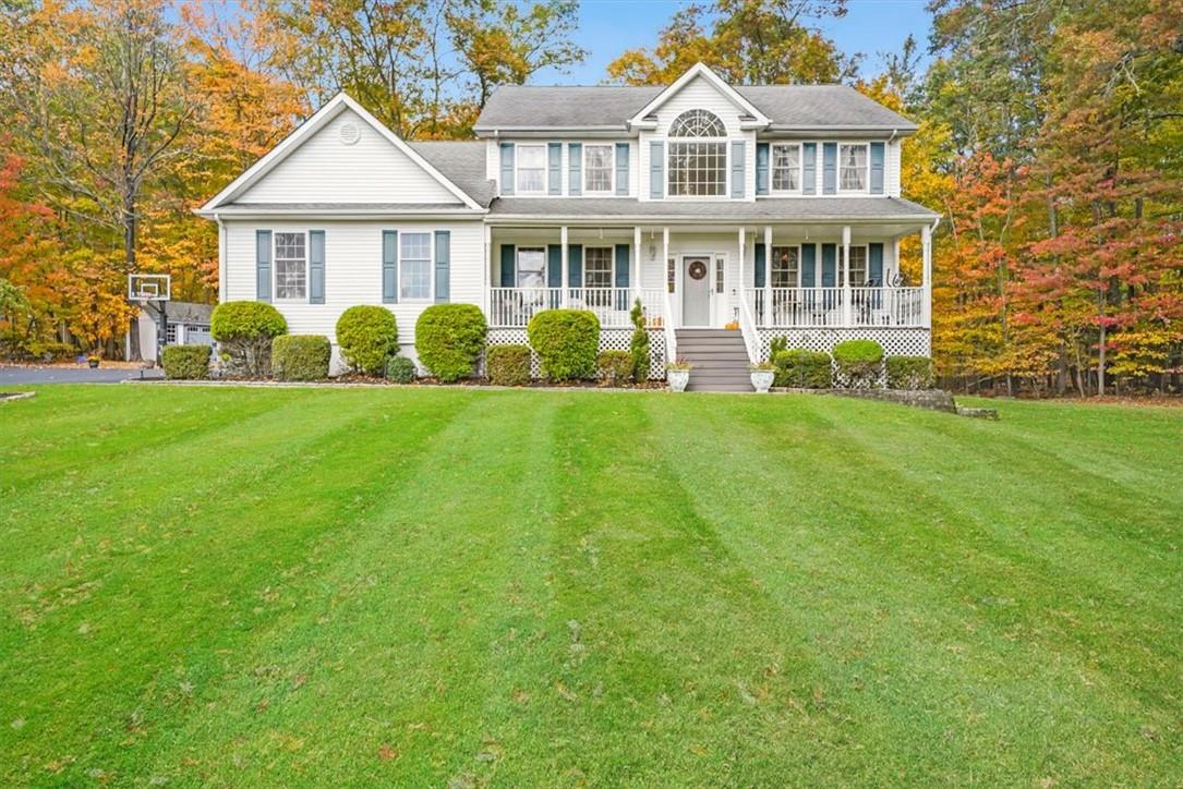 Colonial-style house featuring covered Trex porch and a front yard