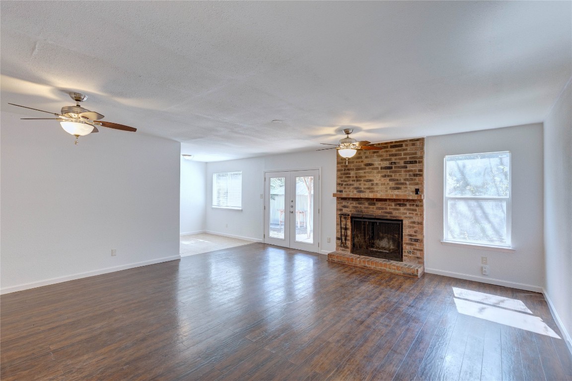 an empty room with windows fireplace and wooden floor