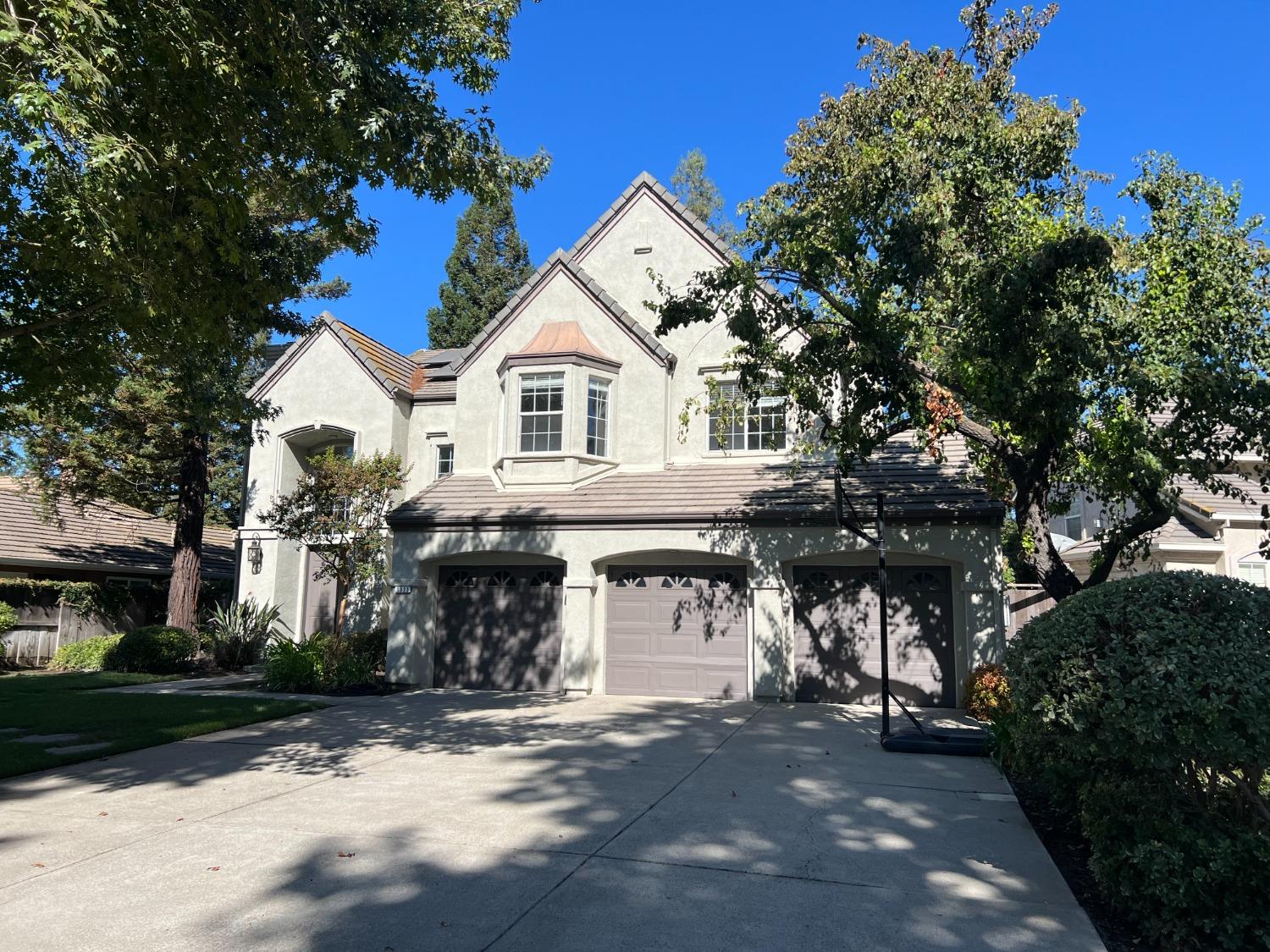 a front view of a house with a garden and trees